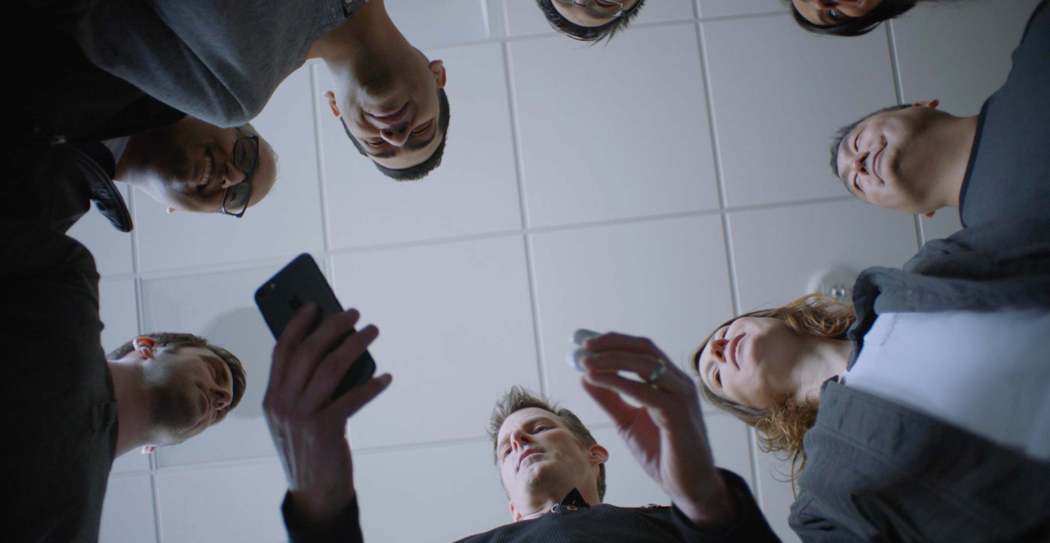 Jason, a manager in Apple&rsquo;s Wireless Software Engineering group, holds an iPhone and a set of AirPods during a group meeting