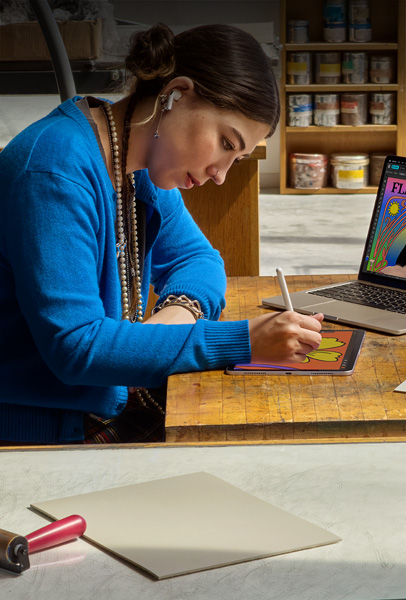 兩位學(xué)生在宿舍房間內(nèi)使用銀色 MacBook 瀏覽內(nèi)容，一位坐在床上，另一位則坐在地板上手持裝置
